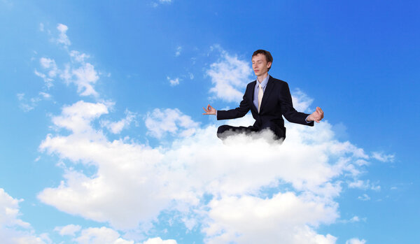 Businessman meditating sitting on the cloud