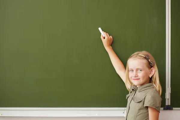 Scoolgirl staande in de buurt van blackboard — Stockfoto