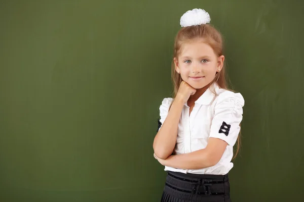 Scoolgirl står nära blackboard — Stockfoto