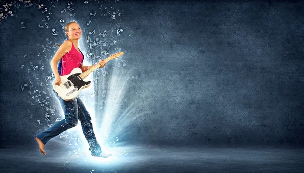 Mujer joven tocando en la guitarra eléctrica y saltando — Foto de Stock