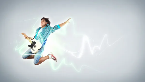 Jovem tocando guitarra electro e pulando — Fotografia de Stock