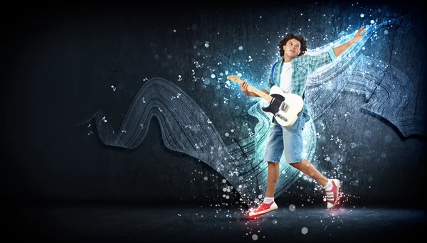 Young man playing on electro guitar and jumping — Stock Photo, Image