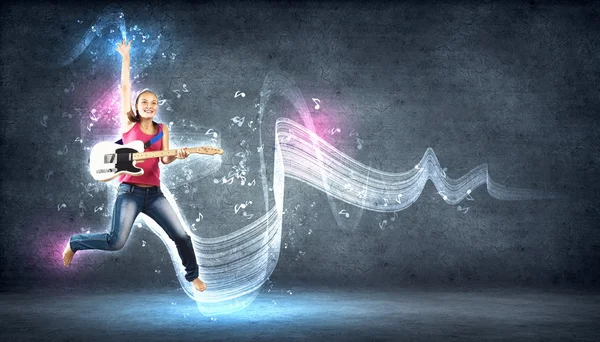 Jeune femme jouant à la guitare électro et sautant — Photo