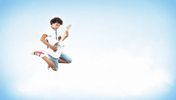 Młody mężczyzna grający na gitarze electro i skoki — Zdjęcie stockowe