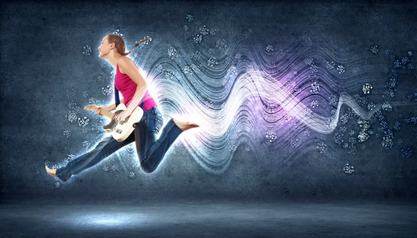Mujer joven tocando en la guitarra eléctrica y saltando —  Fotos de Stock