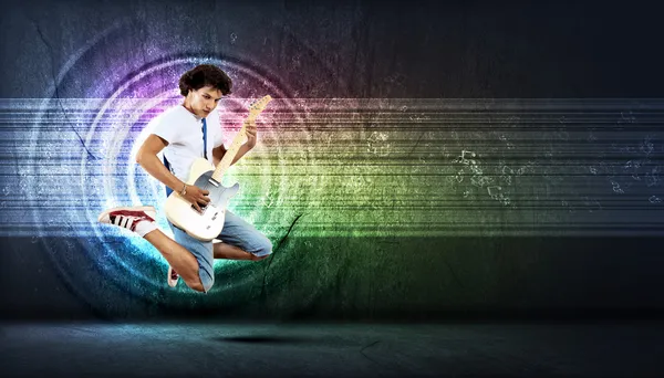 Jeune homme jouant à la guitare électro et sautant — Photo