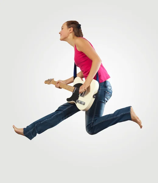 Ung kvinde spiller på electro guitar og hoppe - Stock-foto