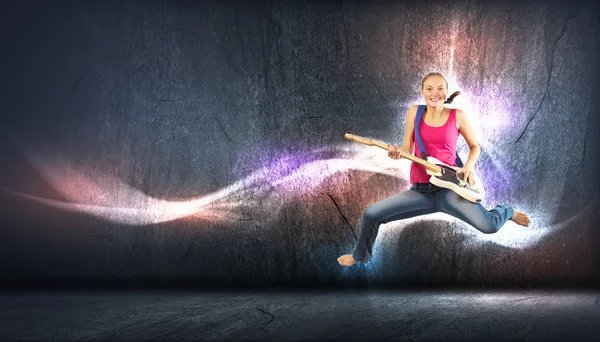 Young woman playing on electro guitar and jumping — Stock Photo, Image
