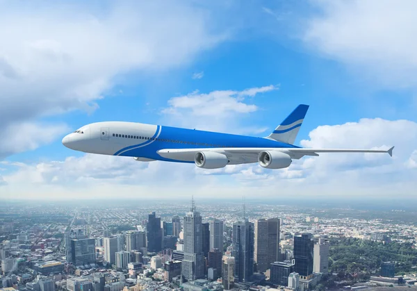 White passenger plane flying above a city — Stock Photo, Image