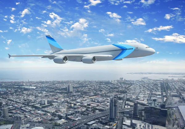都市上空を飛んでいる白い旅客機 — ストック写真