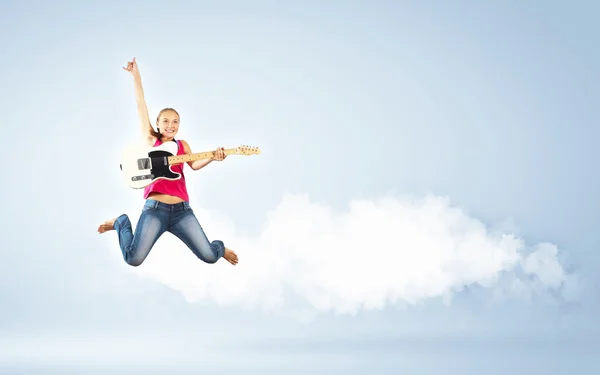 Mujer joven tocando en la guitarra eléctrica y saltando — Foto de Stock