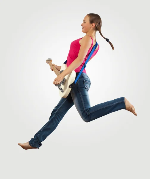 Mujer joven tocando en la guitarra eléctrica y saltando — Foto de Stock