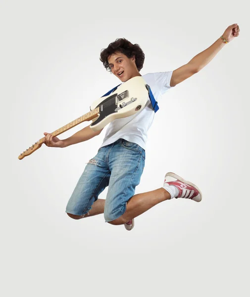 Young man playing on electro guitar and jumping — Stock Photo, Image