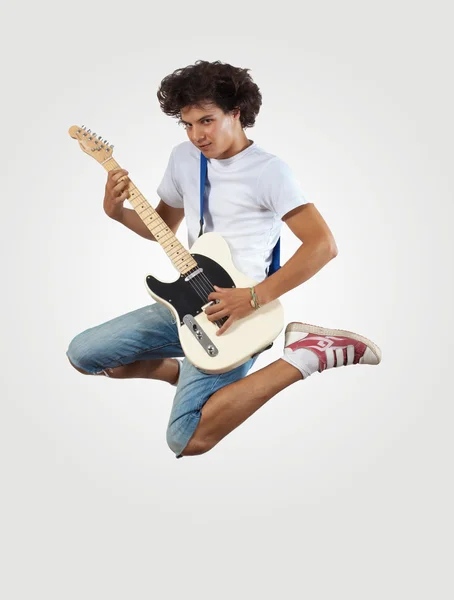 Young man playing on electro guitar and jumping — Stock Photo, Image