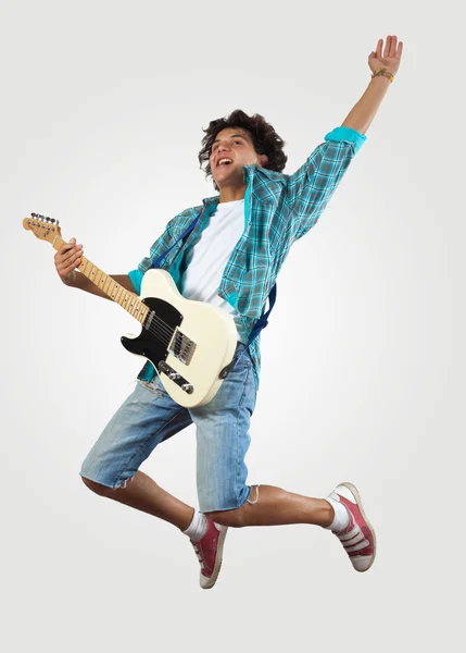 Young man playing on electro guitar and jumping — Stock Photo, Image