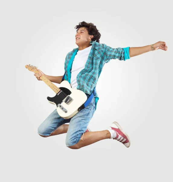 Young man playing on electro guitar and jumping — Stock Photo, Image