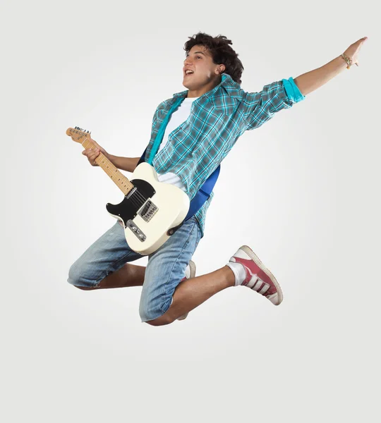 Молодой человек играет на электрогитаре и прыгает — стоковое фото