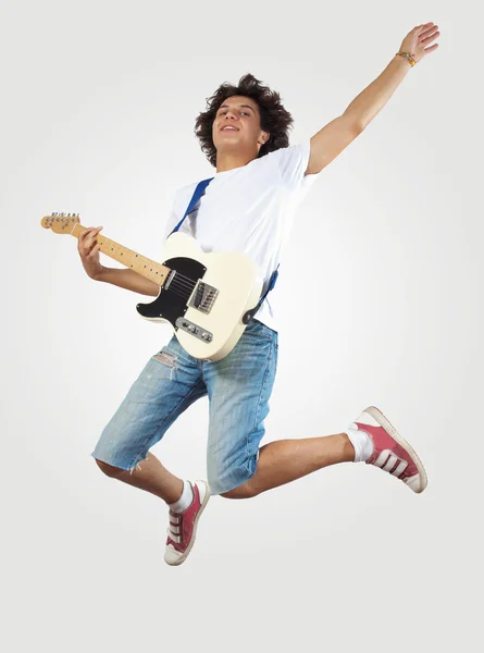 Young man playing on electro guitar and jumping — Stock Photo, Image