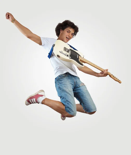 Young man playing on electro guitar and jumping — Stock Photo, Image