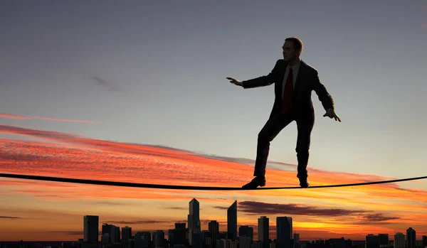 Balancing businessman and cityscape — Stock Photo, Image