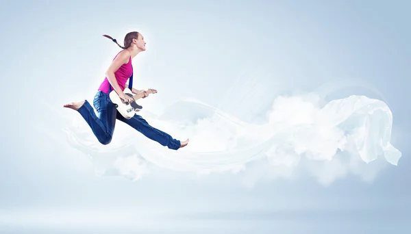 Mujer joven tocando en la guitarra eléctrica y saltando —  Fotos de Stock