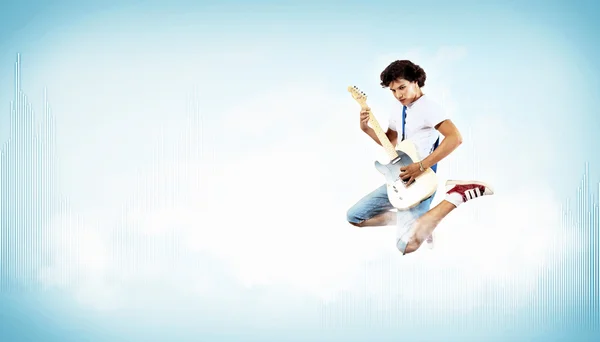 Ung man spela på electro gitarr och hoppning — Stockfoto