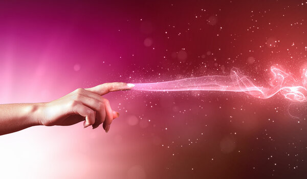 Magical hand conceptual image with sparkles on colour background