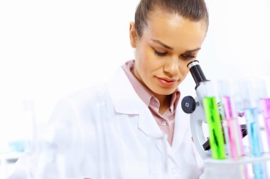 Laboratuvarda sıvılarla çalışan genç bir bilim kadını.