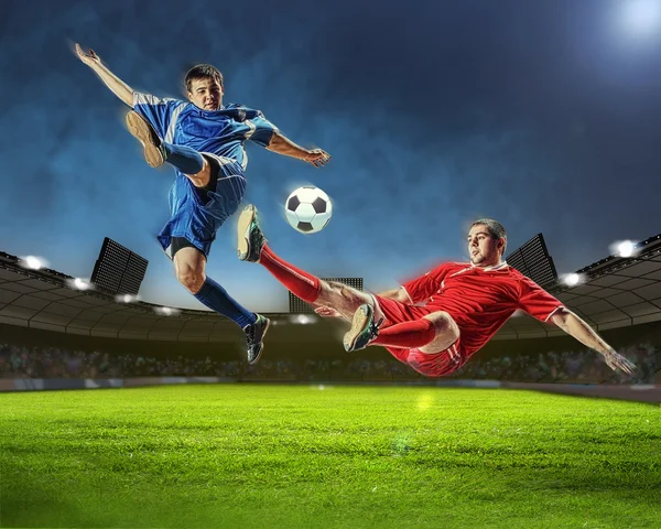 Two football players in jump to strike the ball at the stadium — Stock Photo, Image