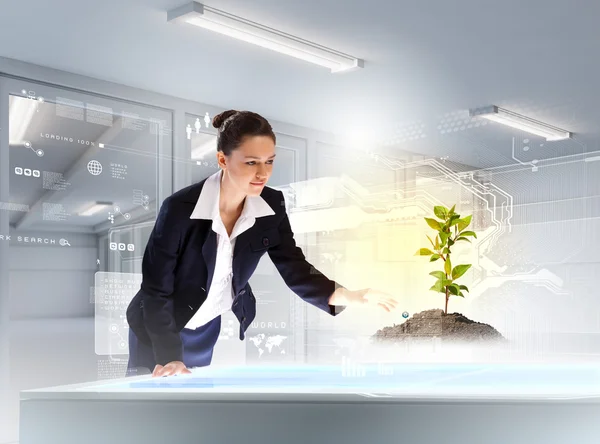 Young businesswoman looking at high-tech image of sprig — Stockfoto