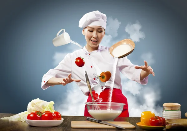 Aziatische vrouw koken met magie tegen een achtergrond met kleur — Stockfoto
