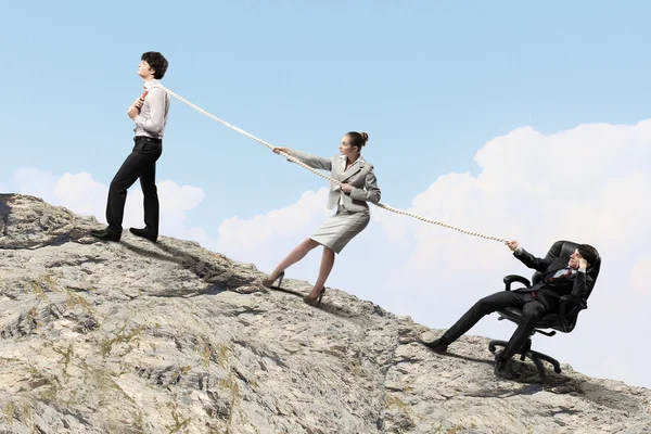 Image of three businesspeople pulling rope atop of mountain — Stock Photo, Image