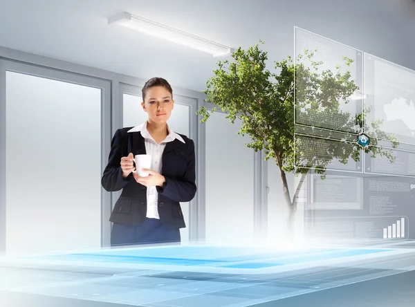 Image of young businesswoman holding cup standing against high-tech picture — Stock Photo, Image