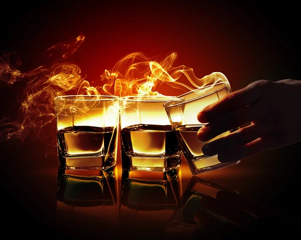 Hand holding one of three glasses of whiskey — Stock Photo, Image