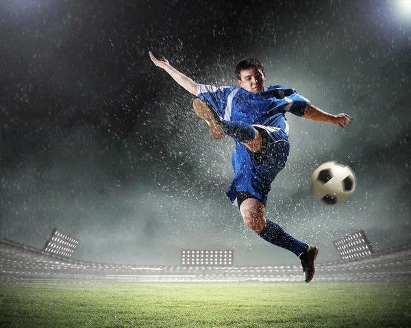Fußballspieler im blauen Hemd schlägt den Ball im Stadion — Stockfoto