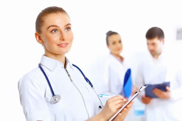 Young female doctor in white uniform with collegues on the background — Stock Photo, Image