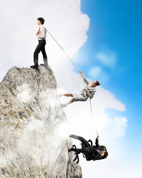Imagem de três empresários puxando corda no topo da montanha — Fotografia de Stock