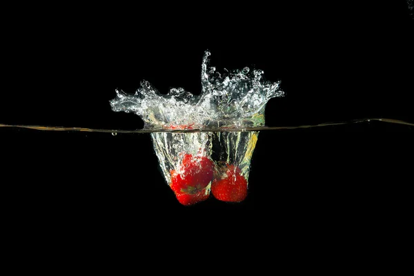 Fragola fresca caduta in acqua con spruzzi — Foto Stock