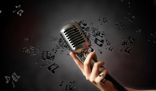 Único microfone retro contra fundo escuro com notas de música — Fotografia de Stock