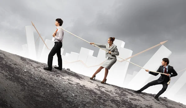 Image of three businesspeople pulling rope atop of mountain — Stock Photo, Image