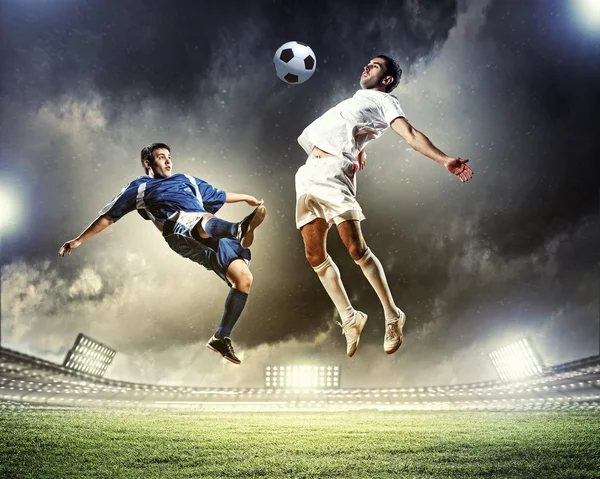 Dos jugadores de fútbol en salto para golpear la pelota en el estadio — Foto de Stock