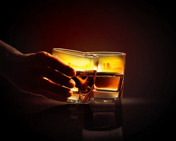 Hand hält eines von zwei Gläsern Whiskey — Stockfoto