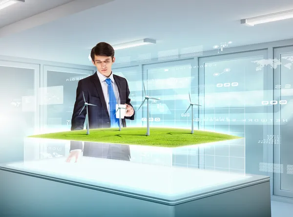 Young businessman looking at high-tech picture of windmills — Stock Photo, Image