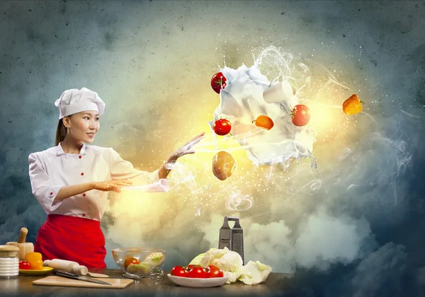 Asiatisk kvinna matlagning med magi mot Cologne bakgrunden — Stockfoto