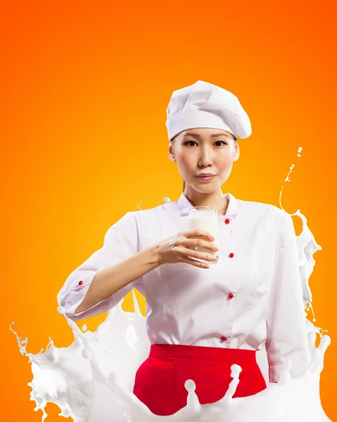 Asian female cook against milk splashes — Stock Photo, Image