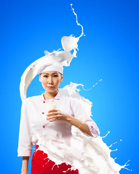 Asian female cook against milk splashes — Stock Photo, Image