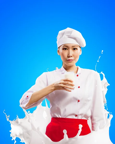 Asian female cook against milk splashes — Stock Photo, Image