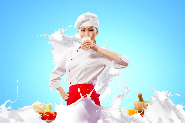 Asian female cook against milk splashes — Stock Photo, Image