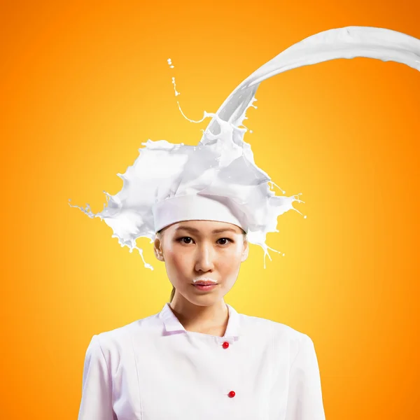 Asian female cook against milk splashes — Stock Photo, Image