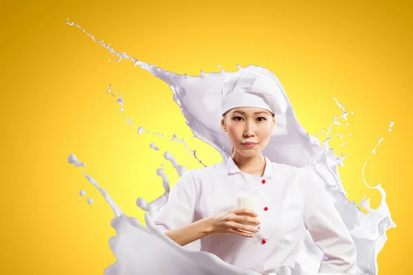 Asian female cook against milk splashes — Stock Photo, Image